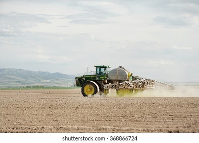 American Falls, Idaho, USA May, 22, 2009 A long arm crop sprayer spraying a freshly planted wheat field.