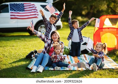 American family spending time together. With USA flags against big suv car outdoor. - Powered by Shutterstock