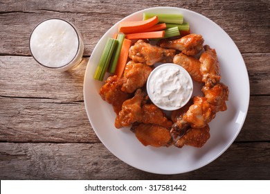 American fast food: buffalo wings with sauce and beer on the table. horizontal view from above