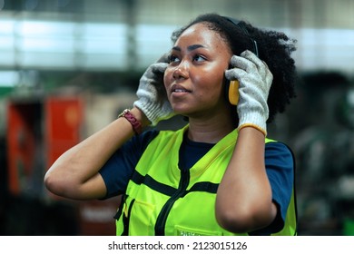 American female worker wearing safety gear .In a heavy industrial factory.