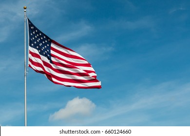 American Flag against the backdrop of a blue sky and clouds.  