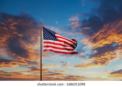An American flag against a blue sky on an old rusty flagpole