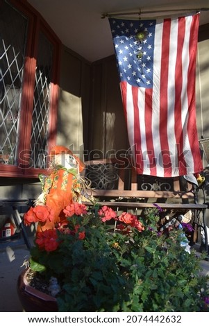American flag and autumn decorations on the front porch of a house