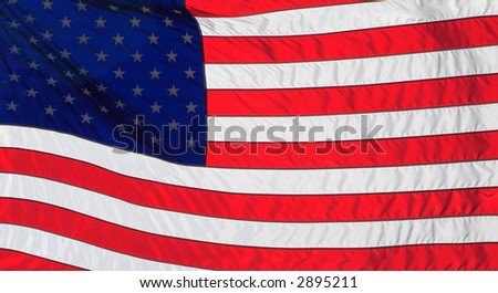 American Flag backlit by the sun and blowing in the wind