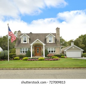 American Flag Beautiful Suburban Brick Cape Cod Style Home Blue Sky Clouds USA