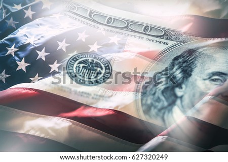 American flag blowing in the  wind and 100 dollars banknotes in the background.