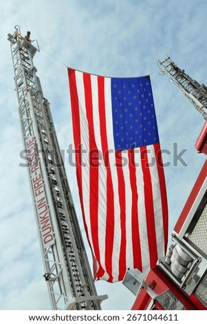 American flag draped between fire truck ladders 