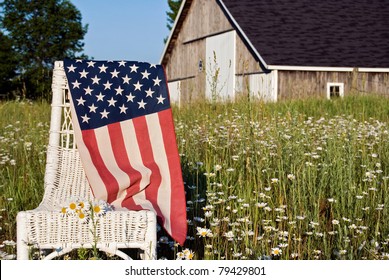 american flag draped over wicker chair in daisy field