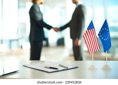 American flag, flag of European Union and business contract on background of two political leaders handshaking  - Shutterstock ID 239452834
