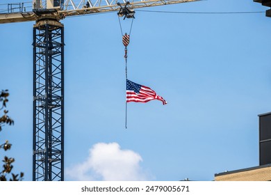 An American flag hanging from a construction crane against a clear blue sky. - Powered by Shutterstock