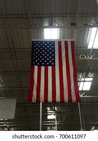 An American Flag Hanging From A High Ceiling In A Building.