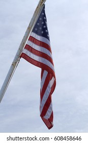 an American flag hanging on a mast with a cloudy sky in the background