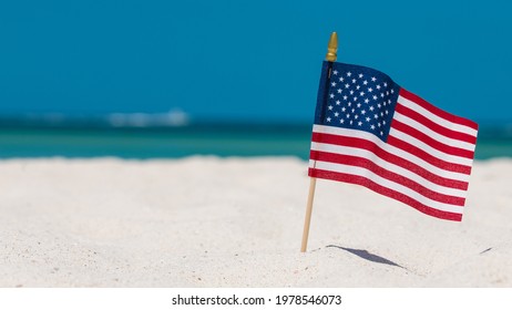 American Flag on the Beach. 4th of July Independence, Memorial or Presidents Day. US starry striped patriotic symbol. United States Holidays. Summer vacations. Ocean sand. Bright sunny day. Salt water