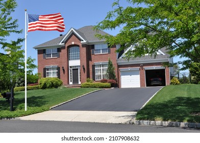 American Flag On Front Lawn Of Suburban Brick Mcmansion In USA