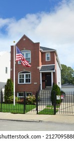 American Flag On Front Lawn Of Brownstone Home With Black Rod Iron Gate In USA