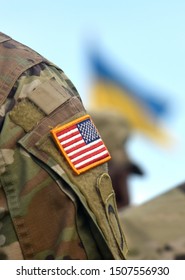 American Flag On Soldiers Arm And Flag Of The Ukraine At Background. US Military Help To Ukraine.