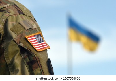 American Flag On Soldiers Arm And Flag Of The Ukraine At Background. US Military Help To Ukraine.