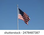 American Flag Pole, Blowing in Wind with Blue Sky Background. America Independence Day July 4th Holiday