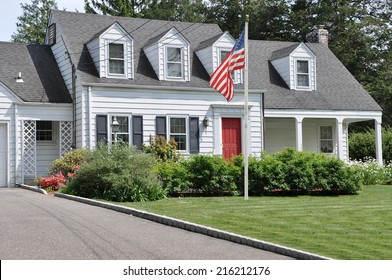 American Flag Pole On Front Yard Lawn Of Suburban Cape Cod Colonial Style Home Sunny Residential Neighborhood USA