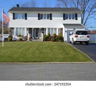 American Flag Pole White Suburban High Ranch Home Car Parked In The Driveway Clear Blue Sky Autumn Day Residential Neighborhood USA