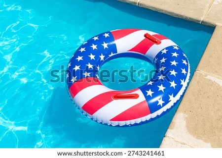 American Flag pool float. Top view of ring circle on blue water background. Summer vacation concept. Vacation in USA concept. 4th of July pool party. High quality photo