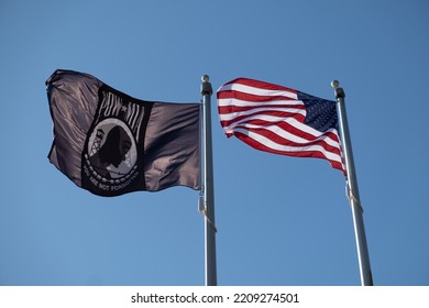 American Flag And POW MIA Flag Flowing Against The Blue Sky