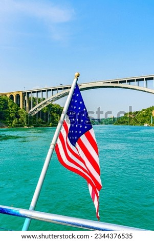 American flag and Rainbow Bridge over the Niagara River. Arch bridge connecting the United States of America and Canada. High quality photo.