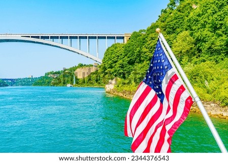American flag and Rainbow Bridge over the Niagara River. Arch bridge connecting the United States of America and Canada. High quality photo.