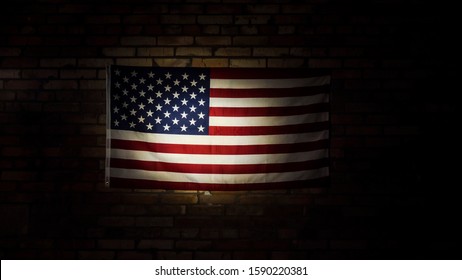 American flag in spotlight hangs on brick wall