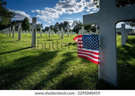 An American flag standing at the gravestone of a killed soldier at the war cemetery in Normandy