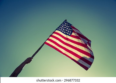 American flag with stars and stripes hold with hands against blue sky ( Filtered image processed vintage effect. ) - Shutterstock ID 296877332