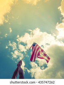 American flag with stars and stripes hold with hands against blue sky ( Filtered image processed vintage effect. ) - Shutterstock ID 435747262