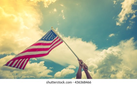 American flag with stars and stripes hold with hands against blue sky ( Filtered image processed vintage effect. ) - Shutterstock ID 436368466
