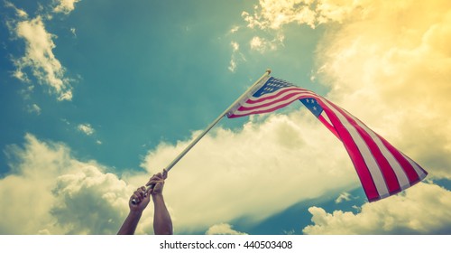 American flag with stars and stripes hold with hands against blue sky ( Filtered image processed vintage effect. ) - Shutterstock ID 440503408