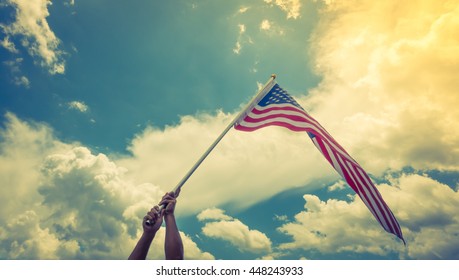 American flag with stars and stripes hold with hands against blue sky ( Filtered image processed vintage effect. ) - Shutterstock ID 448243933