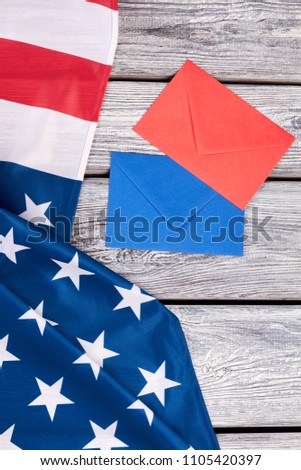 American flag and two colored envelopes. USA patriotic flag and envelopes on old wooden background.