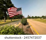 American Flag Waves at the entrance to a cemetery. Park-like setting in the background of view. Located at the entrance to Oak Ridge Cemetery in Springfield, Illinois, USA.