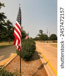 American Flag Waves at the entrance to a cemetery. Park-like setting in the background of view. Located at the entrance to Oak Ridge Cemetery in Springfield, Illinois, USA.