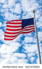 The American Flag Waves In The Wind As The Blue Sky Serves As A Back Drop.