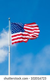 American flag waving against blue sky with room for text.