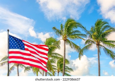 American flag waving against palm trees on blue sky background - Powered by Shutterstock