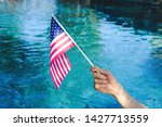 American flag waving in celebration with pool water in background.  Fourth of July or Memorial Day holiday concept.