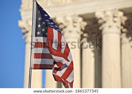 American flag waving in front of the U.S. Supreme Court building columns on Capitol Hill in Washington, DC