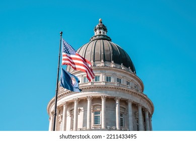 American flag waving at State Capitol Building in Salt Lake city. Low angle view of dome structure with blue sky in background. Famous national political landmark in city during summer. - Powered by Shutterstock
