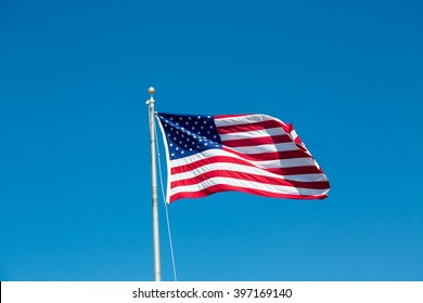 American Flag Waving In The Wind On A Blue Sky