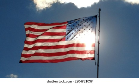 An American Flag Waving In The Wind With The Sun Lighting It Up