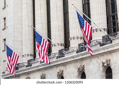 American flags on exterior facade of New york Stock Exchange, largest stock exchange in world by market capitalization and most powerful global financial institute. Wall street, New York City, USA.