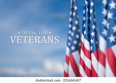 American flags with Text Thank You Veterans on blue sky background.