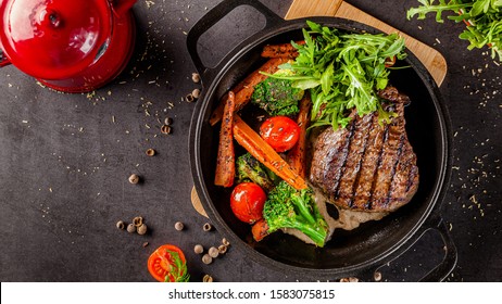 American food concept. Grilled beef steak with grilled vegetables, with carrots, cherry tomatoes, broccoli, in a cast iron pan. copy space - Powered by Shutterstock