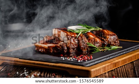 American food concept. Grilled pork ribs with grilled sauce, with smoke, spices and rosemary. Background image. copy space